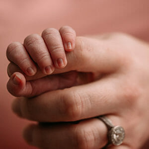Baby holding adult hand with wedding ring